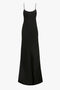 A long, sleeveless black slip dress made from elegant crepe back satin, featuring thin spaghetti straps and a subtle flare at the hem for a chic silhouette. This is the Floor-Length Cami Dress In Black by Victoria Beckham.