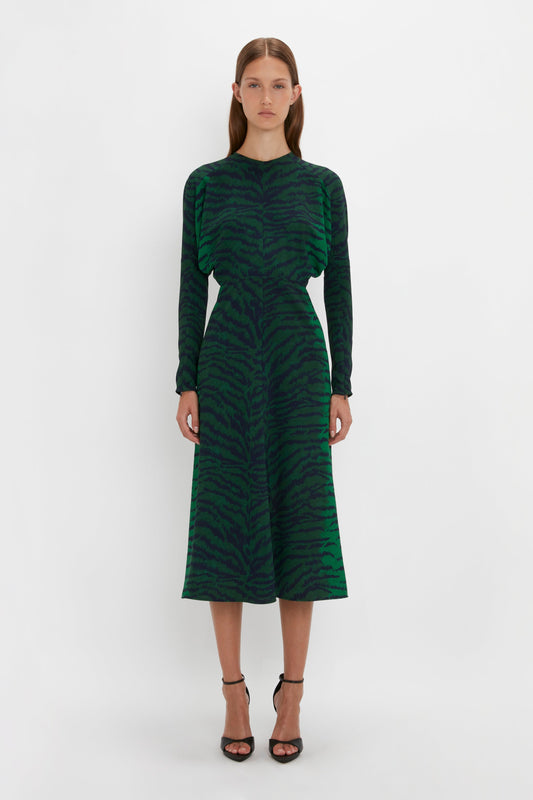 A woman in a Victoria Beckham Dolman Midi Dress In Green-Navy Tiger Print with long sleeves, standing against a white background.