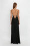 A woman with long hair is shown from the back, wearing a Floor-Length Cami Dress In Black by Victoria Beckham, made of crepe back satin, featuring thin straps and an open back design.