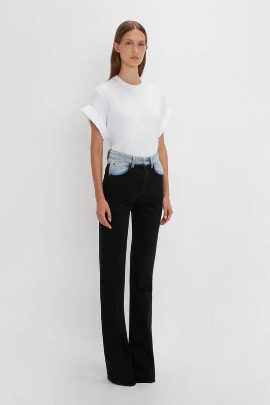 A woman in a white t-shirt and black relaxed fit Julia Jeans In Contrast Wash by Victoria Beckham stands against a plain background.