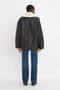 Person seen from the back wearing a Shearling Coat In Monochrome by Victoria Beckham with blue jeans, standing on a white background.