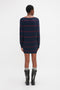 Person wearing a Victoria Beckham Frame Detail Jumper Dress In Navy-Red with a mid-weight knit and black boots, standing and facing away from the camera against a plain white background.