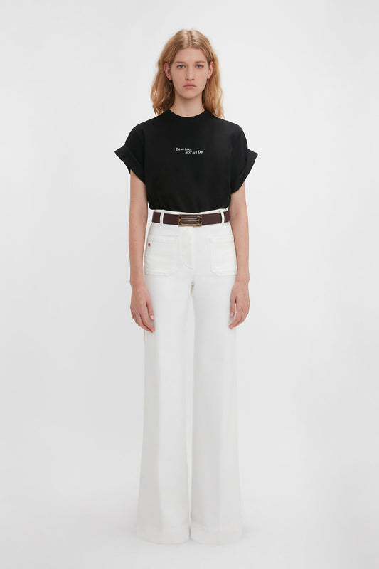 Woman wearing a Victoria Beckham 'Do As I Say, Not As I Do' Slogan T-Shirt In Black and white wide-leg trousers, standing against a plain white background.
