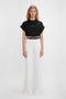 Woman wearing a Victoria Beckham 'Do As I Say, Not As I Do' Slogan T-Shirt In Black and white wide-leg trousers, standing against a plain white background.