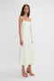 A woman with long, dark hair is wearing a sleeveless, Exclusive Panelled Midi Cami Dress In Vanilla by Victoria Beckham and beige high-heeled sandals. She is standing against a plain white background.