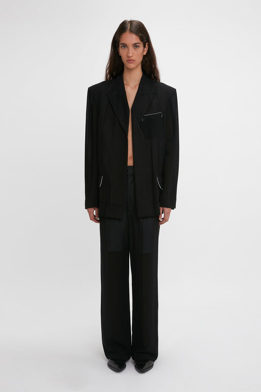 A woman in a Victoria Beckham Fold Detail Tailored Jacket In Black with an open blazer revealing a bare midriff, standing against a plain white background.