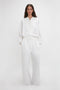 A woman in a white jumpsuit with an adjustable drawstring waistband stands against a plain background. 
    - A woman in Victoria Beckham Drawstring Pyjama Trouser In Washed White stands against a plain background.