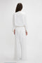 Woman in a classy Victoria Beckham drawstring pyjama trouser in washed white standing with her back to the camera against a plain background.