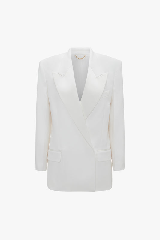 A white double-breasted wool-blend blazer with a deep V neckline, notched lapels, and structured shoulders. The Exclusive Double Breasted Tuxedo Jacket In Ivory by Victoria Beckham has two front flap pockets and a clean, minimalist design perfect for black-tie occasions.
