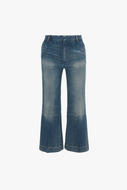 Blue flared jeans with a Victoria Beckham Cropped Kick Jean In Indigrey Wash effect and visible seams, isolated on a white background.