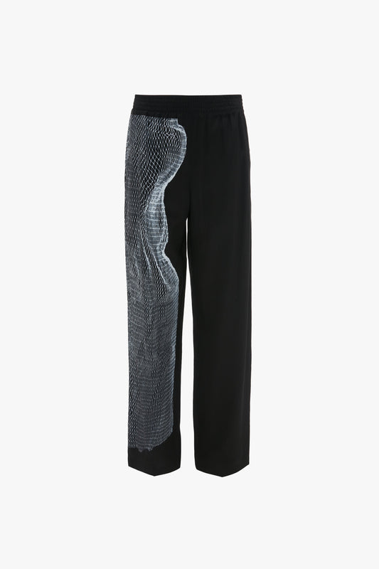 Victoria Beckham Pyjama Trouser In Black-White Contorted Net with a blue, twisted net print on one side. The trousers feature a straight-leg cut and an elastic waistband. The background is plain white.