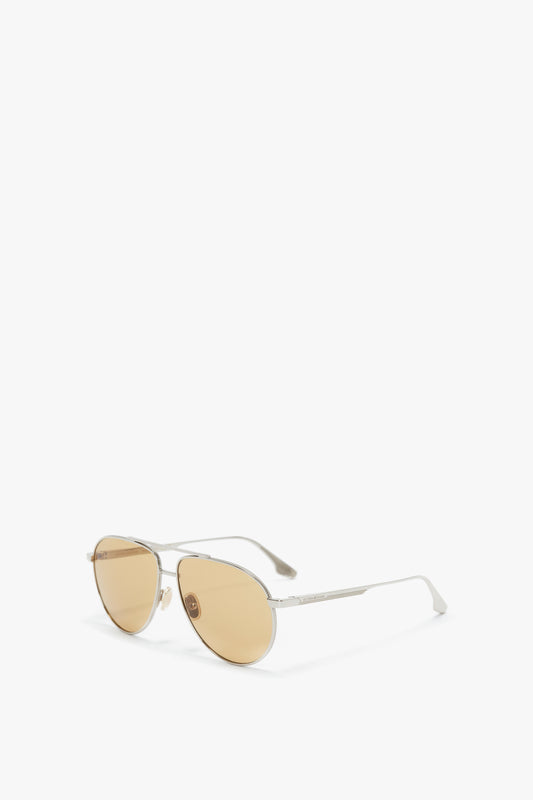 A pair of Victoria Beckham V Metal Pilot sunglasses in silver-brown with gold-tinted lenses and adjustable nose pads, isolated on a white background.