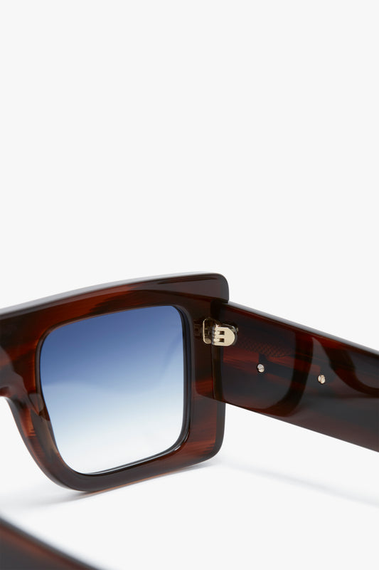 Close-up view of a pair of Victoria Beckham Oversized Frame Sunglasses In Brown Horn with a bold oversized frame in a rich Brown Horn colourway and blue gradient lenses. The image focuses on the hinge and arm details.