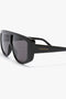 Close-up of Acetate Visor Sunglasses In Black with thick, oversized frames. The brand name "Victoria Beckham" is printed on the temple, and the black tonal lenses complete the chic look of these Victoria Beckham eyewear pieces.