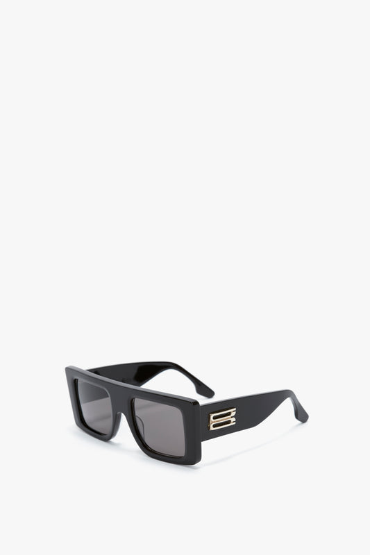 A pair of Victoria Beckham Oversized Frame Sunglasses In Black with dark lenses and a decorative metallic accent on the temples, reminiscent of the SS24 runway, placed on a plain white background.
