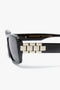 Close-up of Chain Detail Rectangular Frame Sunglasses In Black with gold chain-link detail on the temples, set against a white background. Victoria Beckham eyewear at its finest.