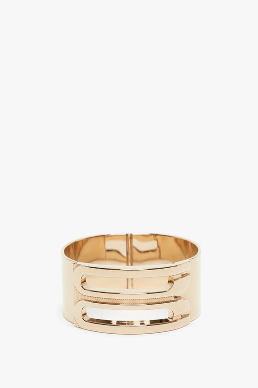 Gold-plated brass bangle bracelet with a wide band, featuring two slotted cutout designs on the front. This Exclusive Frame Bracelet In Gold also showcases a subtle Victoria Beckham logo for an added touch of elegance.