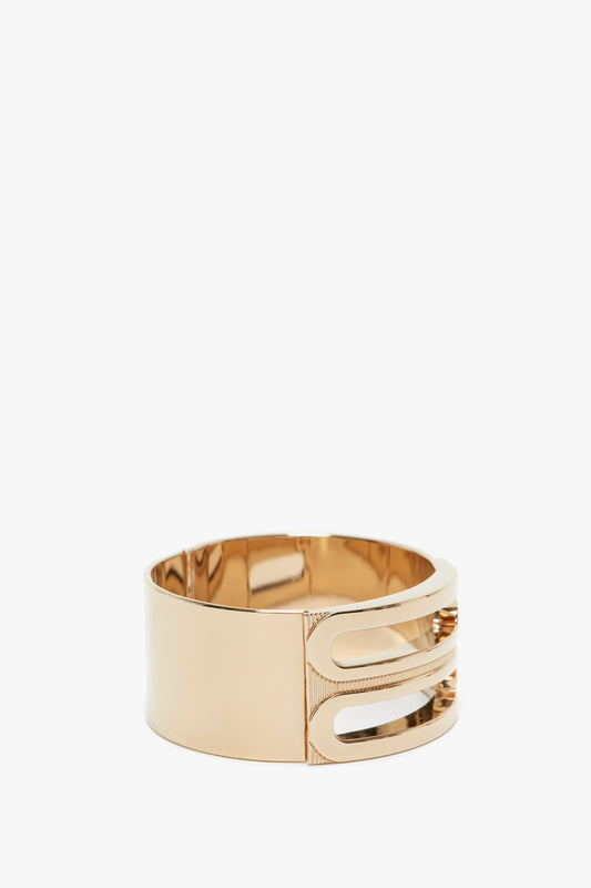 A gold-colored, gold-plated brass bracelet with a wide band and an open, geometric design on one side, invoking the elegance of a Victoria Beckham Exclusive Frame Bracelet In Gold.