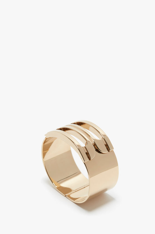 An Exclusive Frame Bracelet In Gold featuring a wide, solid band that elegantly splits into three parallel bands on the top, adorned with the Victoria Beckham logo.
