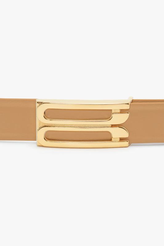 Close-up of a Victoria Beckham Frame Belt In Camel Leather with a shiny gold buckle, isolated on a white background.
