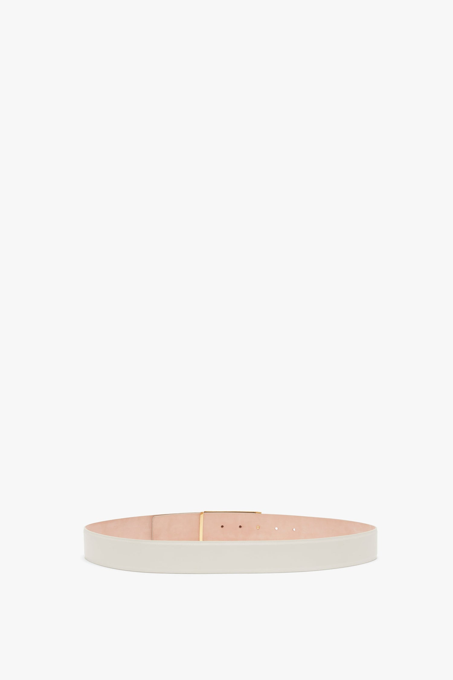 A Victoria Beckham Jumbo Frame Belt In Latte Leather made of pristine white calf leather with elegant gold hardware is displayed in a circular position on a white background.