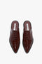 A pair of luxurious calfskin leather, lace-up, pointed-toe slip-on shoes with brogue detailing, viewed from above: Flat Lace Up Mules In Bordeaux Leather by Victoria Beckham.