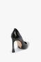 V Pump In Black Brushed Leather by Victoria Beckham with a pointed toe and a glossy finish, viewed from the back angle on a plain light background, features a sculptural heel that adds an artistic touch.