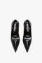 A pair of black patent leather pointed-toe V Pump In Black Brushed Leather with sculptural heels and black insoles, viewed from above, by Victoria Beckham.