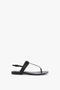 A black Flat Chain Sandal In Black Leather by Victoria Beckham crafted from calfskin leather with a slender, adjustable ankle strap and toe post, featuring minimalist design and simple buckle closure.