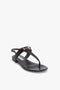 A single black Flat Chain Sandal In Black Leather by Victoria Beckham with a flat sole, adjustable ankle strap, and gold buckle accent on the upper strap, crafted from calfskin leather and displayed against a plain white background.