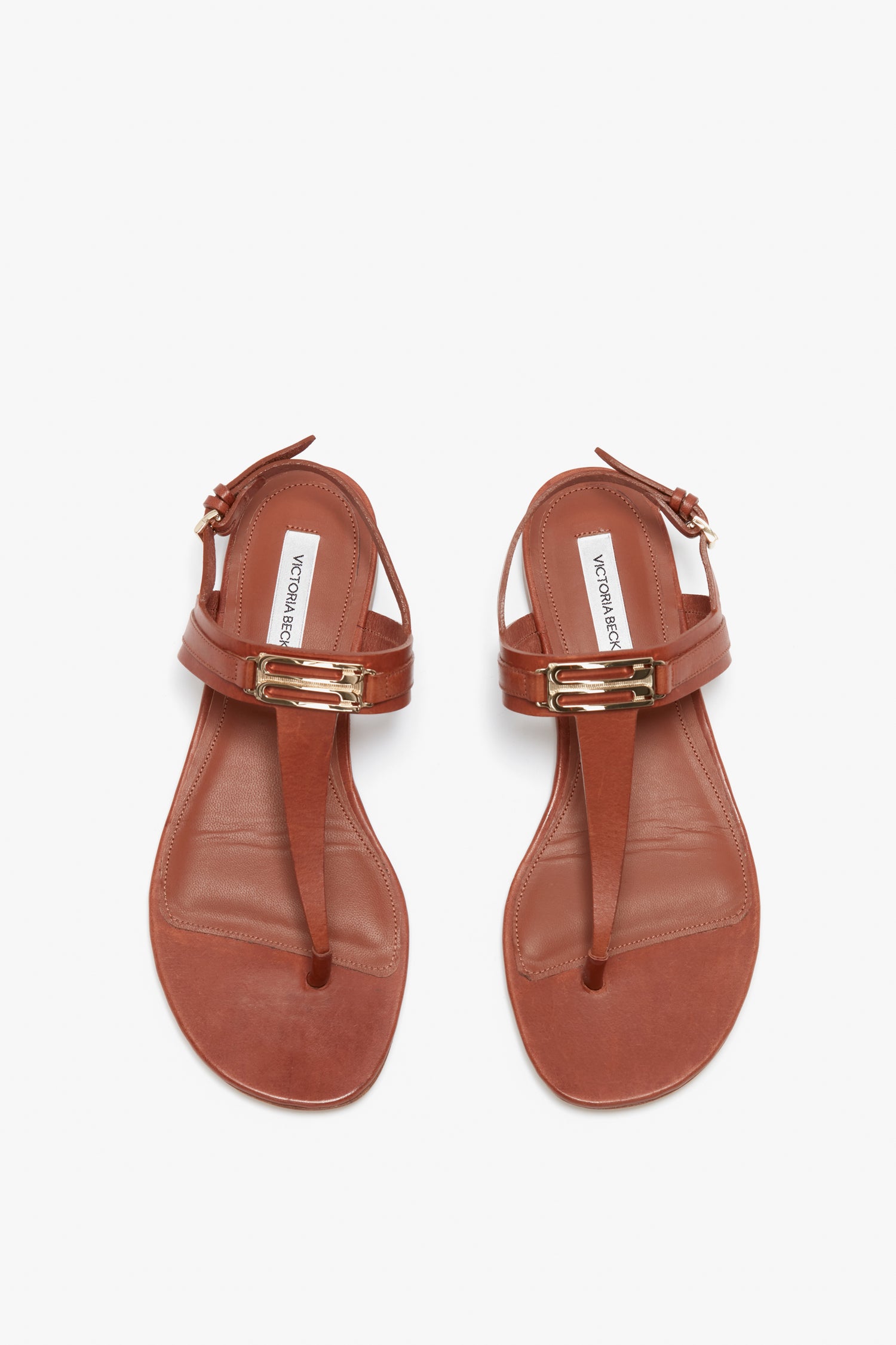 A pair of Victoria Beckham Flat Chain Sandals in Tan Leather with an adjustable ankle strap and gold accents on a white background.