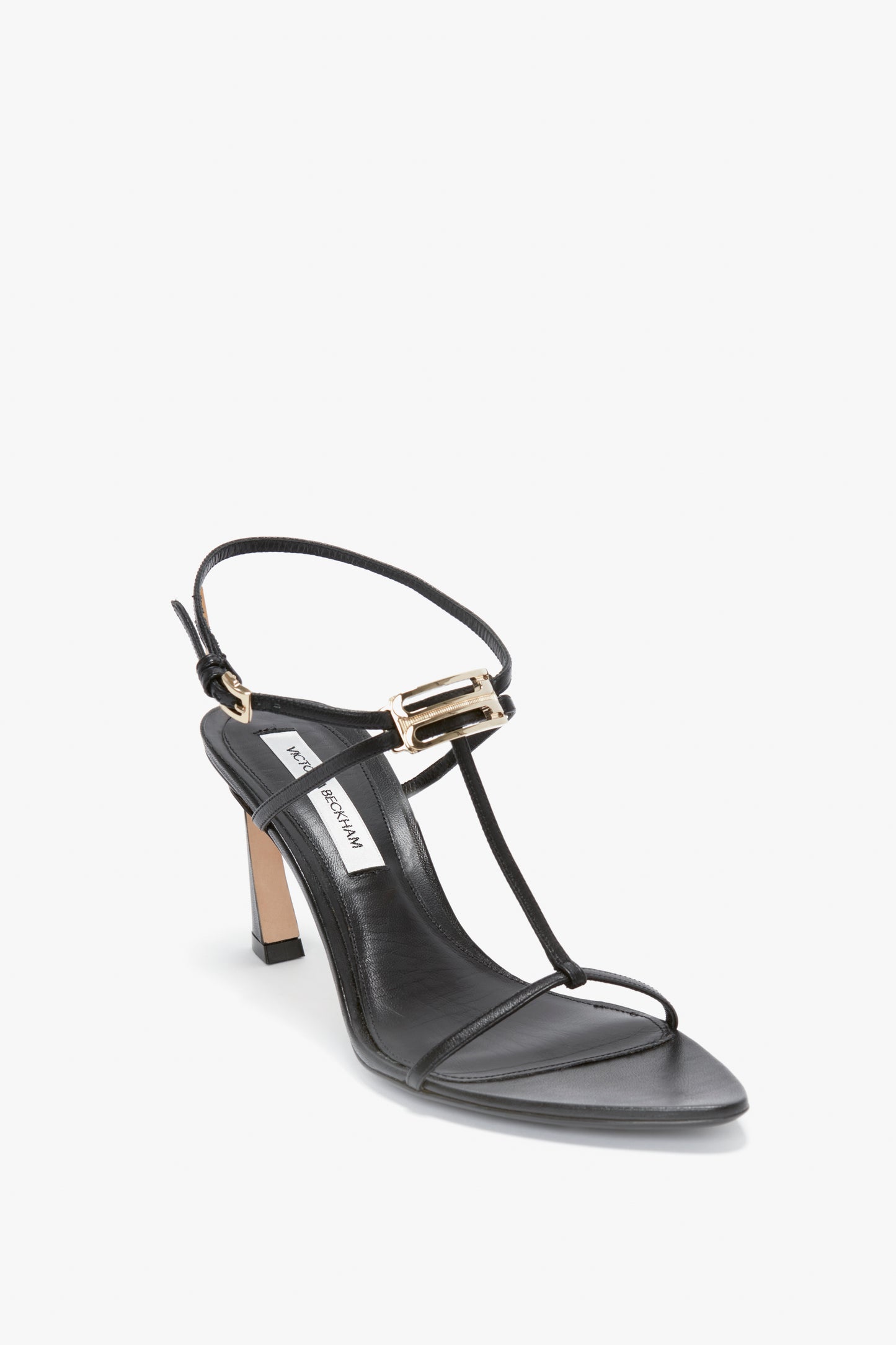 A Victoria Beckham Frame Detail Sandal In Black Leather with thin nappa leather straps, an adjustable ankle strap, and a gold buckle.