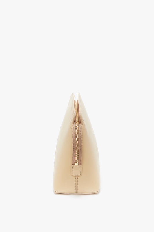 Side view of a beige handbag with a zipper closure and a structured silhouette, echoing Victoria’s favourite Victoria Clutch Bag In Sesame Leather from the SS24 runway by Victoria Beckham.