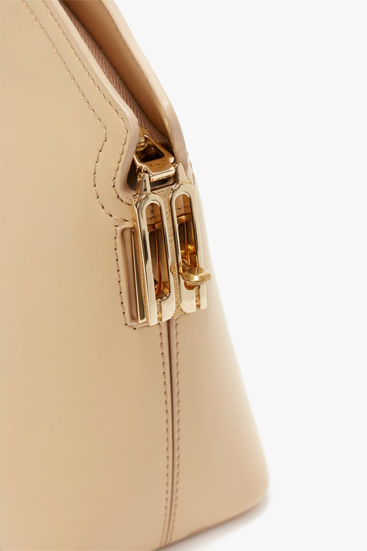 Close-up view of a beige handbag featuring gold hardware and detailed stitching, reminiscent of Victoria's favorite Victoria Clutch Bag In Sesame Leather by Victoria Beckham seen on the SS24 runway.