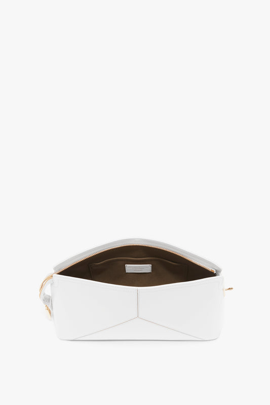 An Exclusive Victoria Clutch Bag In White Leather by Victoria Beckham with a zippered opening, revealing a brown interior and a small pocket.