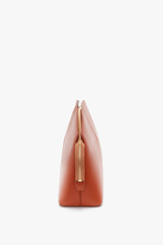 Side view of a Victoria Beckham Victoria Clutch Bag In Tan Leather made from glossy calf leather with a gold zipper, displayed against a white background.