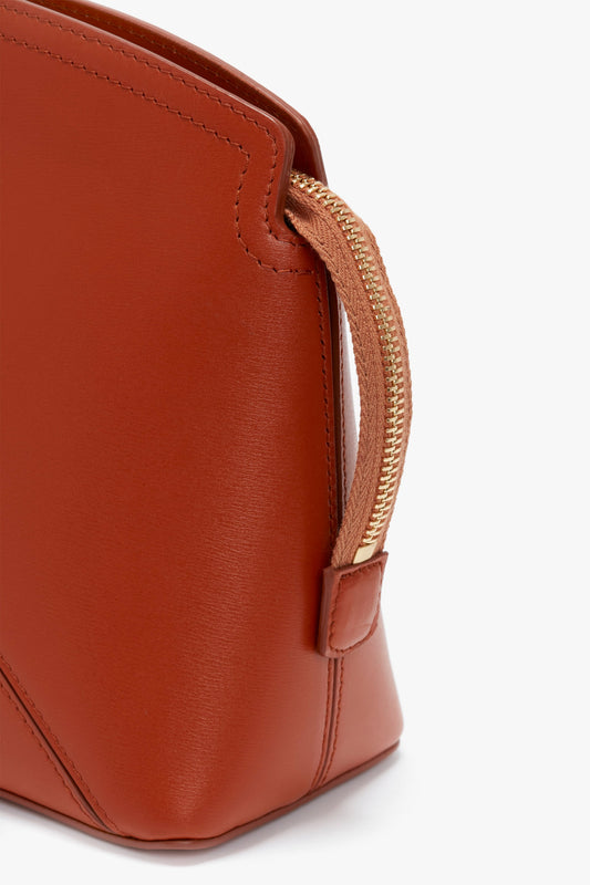 Close-up of the Victoria Clutch Bag In Tan Leather by Victoria Beckham featuring a gold zipper and minimalist design, reminiscent of Victoria Beckham's signature aesthetic.
