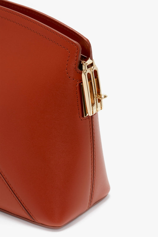 Close-up of a Victoria Beckham Victoria Clutch Bag In Tan Leather featuring a gold clasp on the side.