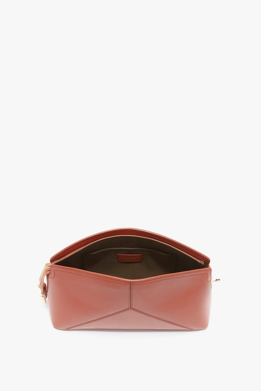 Open the Victoria Beckham Victoria Clutch Bag In Tan Leather with a gold zipper, revealing the interior compartments. Made from glossy calf leather, this accessory exudes sophistication reminiscent of Victoria Beckham's signature style.