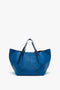 A Victoria Beckham W11 Medium Tote Bag In Vibrant Blue with a wide opening, double handles, and a sleek, minimalist design crafted from grained leather.