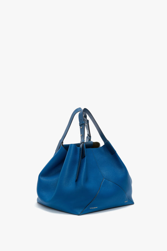 A Victoria Beckham W11 Medium Tote Bag in Vibrant Blue grained leather with a slouchy design and strap handles, showcased against a plain white background.