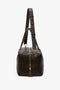 A Medium Gym Bag In Chocolate Brown by Victoria Beckham, featuring gold hardware, a front zipper pocket, and an adjustable shoulder strap against a plain white background.