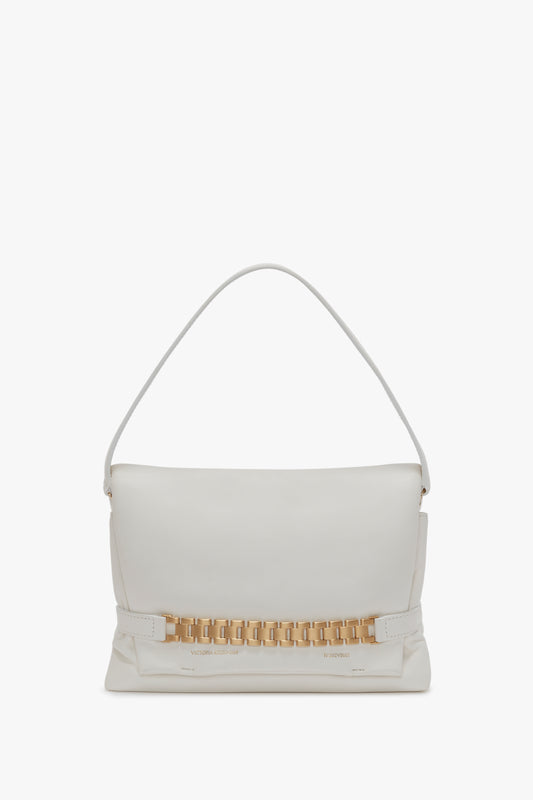 A Victoria Beckham Puffy Chain Pouch Bag With Strap In White Leather featuring a white design with a gold rectangular chain decoration near the bottom and a stylish detachable shoulder strap.