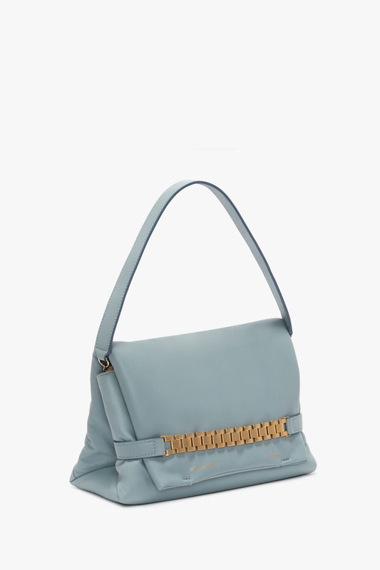 Light blue Victoria Beckham Puffy Chain Pouch With Strap In Ice Leather handbag with a structured design and a gold metallic embellishment on the front, isolated on a white background.