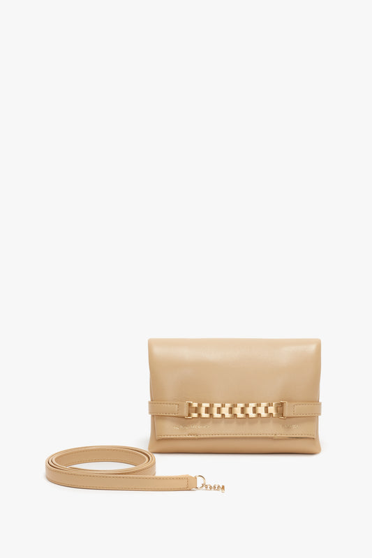 A Mini Pouch With Long Strap In Sesame Leather crossbody shoulder bag with a decorative chain detail on the front and a long strap, displayed against a white background by Victoria Beckham.