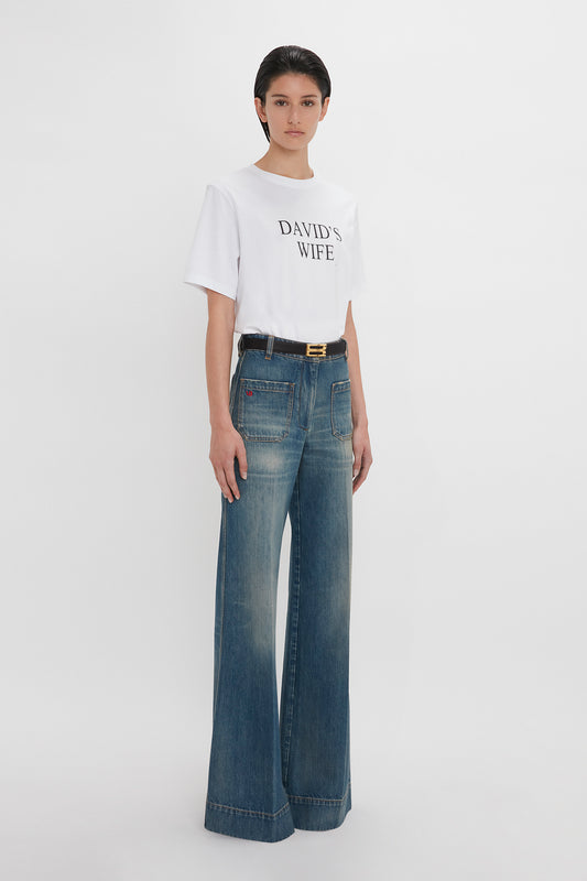 A woman in a white t-shirt reading "david's wife" and vintage denim Alina jeans stands against a plain white background.
