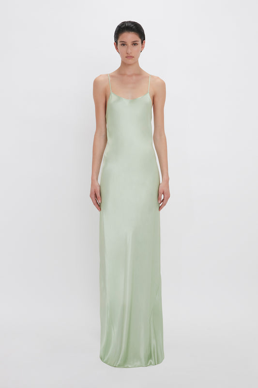 Woman in an Exclusive Low Back Cami Floor-Length Dress In Jade by Victoria Beckham, standing against a white background.