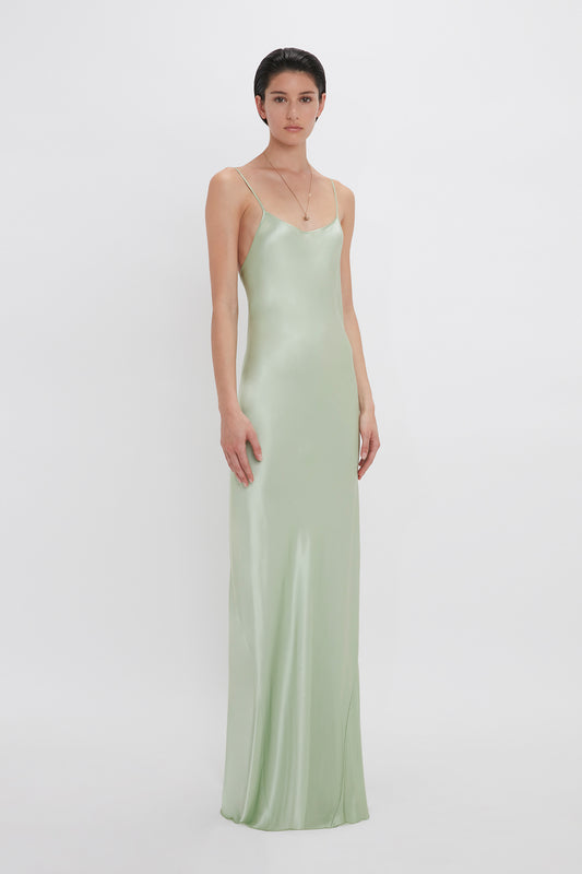 Woman in a Victoria Beckham Exclusive Low Back Cami Floor-Length Dress In Jade standing against a white background.
