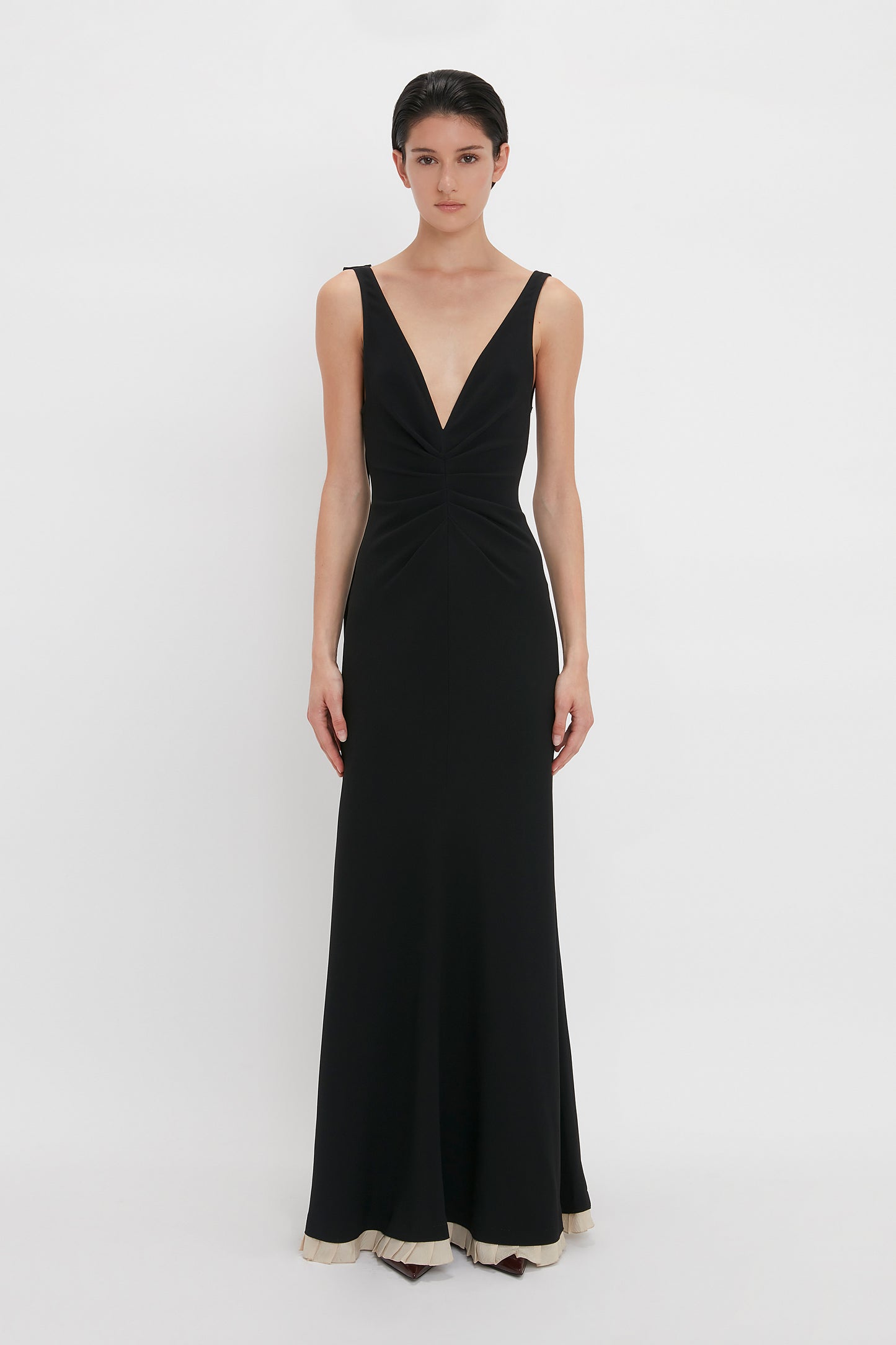 A person wearing the Victoria Beckham V-Neck Gathered Waist Floor-Length Gown In Black.