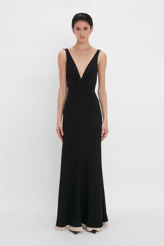 A person wearing the Victoria Beckham V-Neck Gathered Waist Floor-Length Gown In Black.